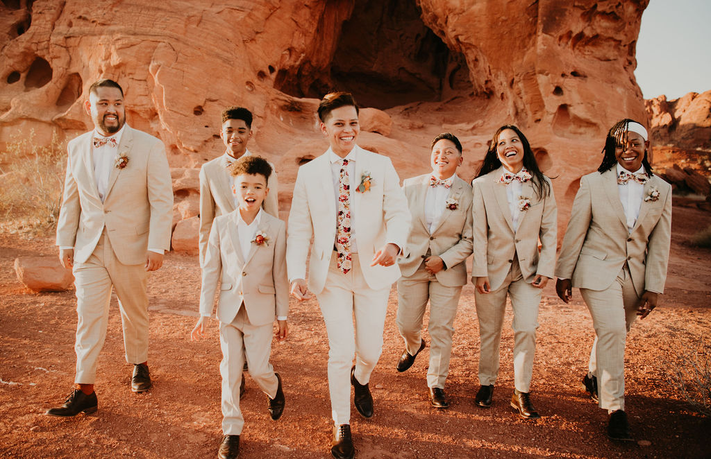 Wedding party in cream suits walking towards camera 