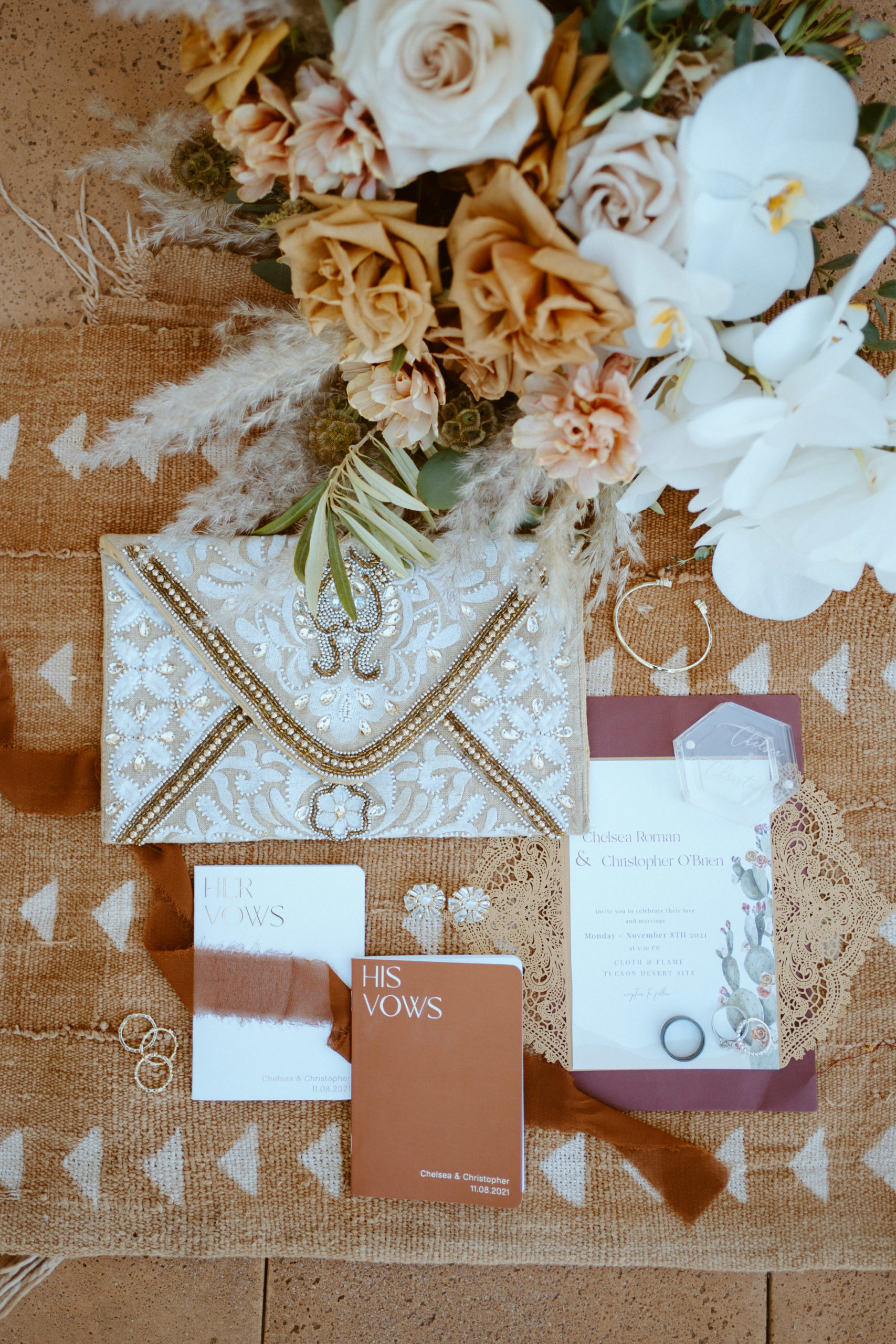 wedding flat lay with flower, jewelry, vow books and stationary