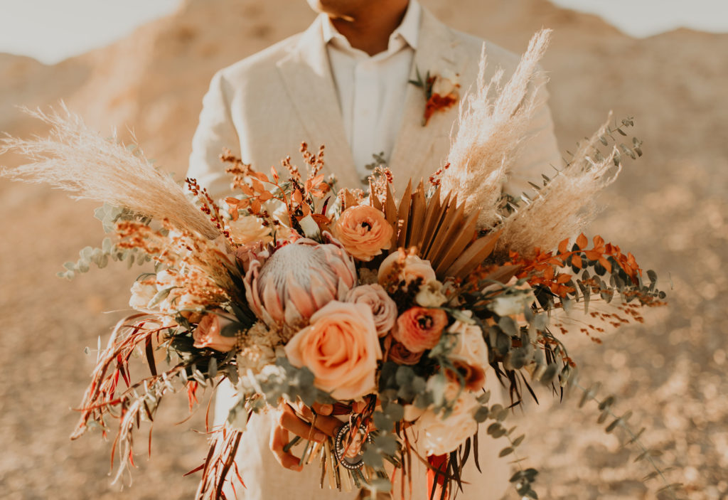 man holding warm-colored bridal bouquet