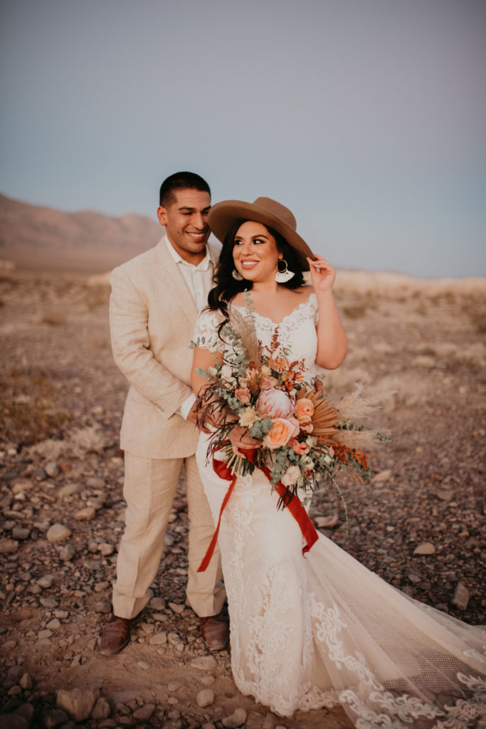 bride and groom standing in desert