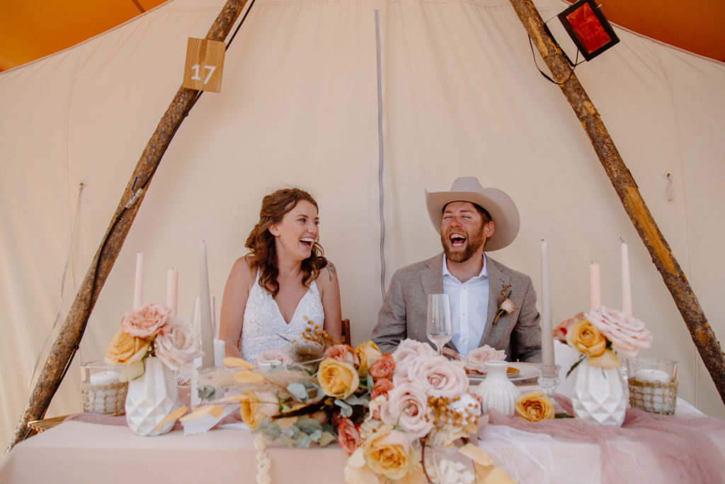 Newlyweds laughing at sweetheart table 