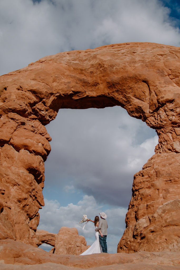 Newlyweds under rock arch during  Adventurous Elopement in Canyonlands National Park