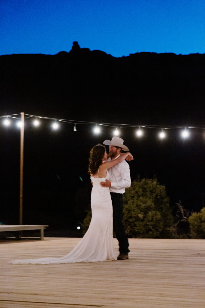 Newlyweds dancing along under lights at night 