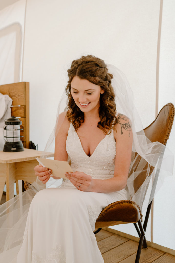 Bride smiling readying letter while getting ready 