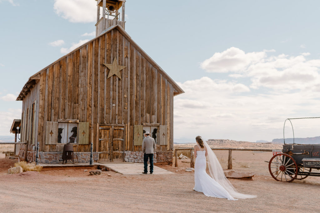 Groom awaits first look near beautiful barn while bride approaches 