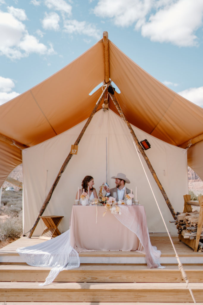 Couple enjoying sweetheart table on patio of glamping tent 