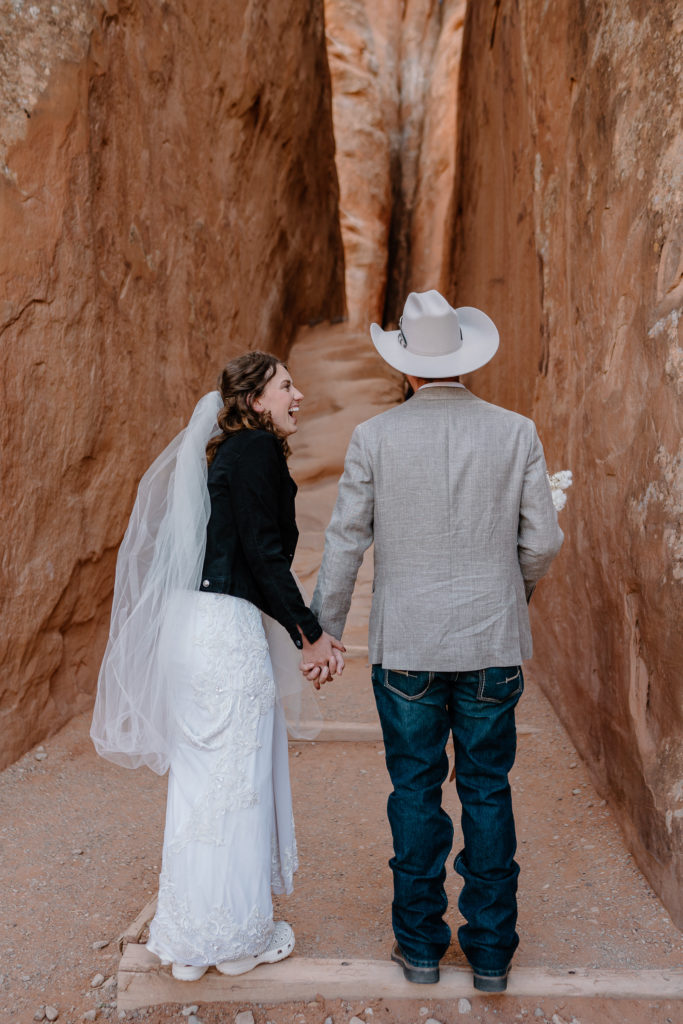 Couple laughing while walking through narrow rock structure near Sand Dune Arch