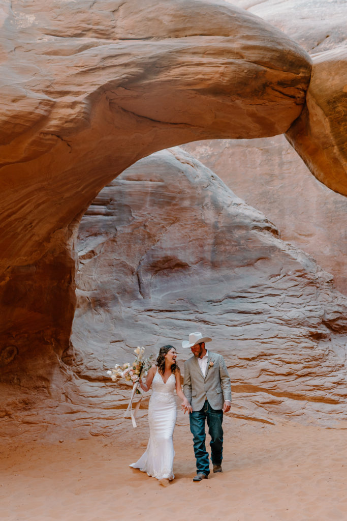 Bride and Groom walking to ceremony at Sand Dune Arch