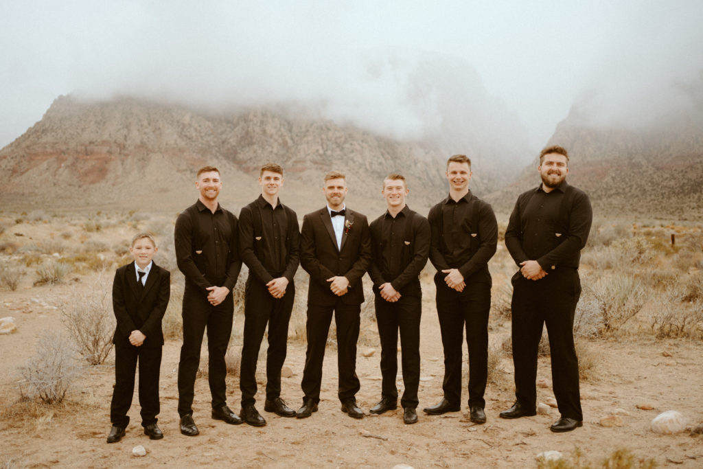 Groomsmen standing in Red Rock Canyon wearing all black for Red Rock Bridals & Simple Affair Micro-Wedding 