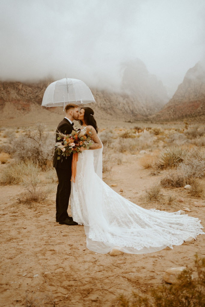 Bride and Groom kissing under transparent umbrella for Red Rock Bridals & Simple Affair Micro-Wedding 