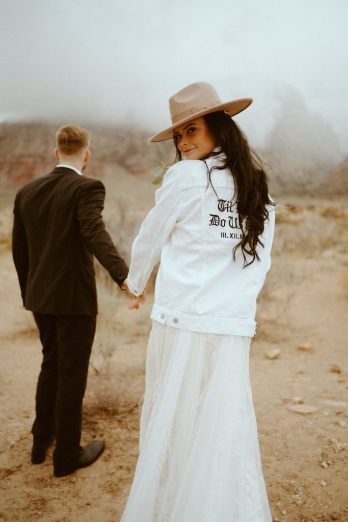 Groom walking with Bride in felt hat and Til Death Do Us Part White Jacket for Red Rock Bridals & Simple Affair Micro-Wedding 