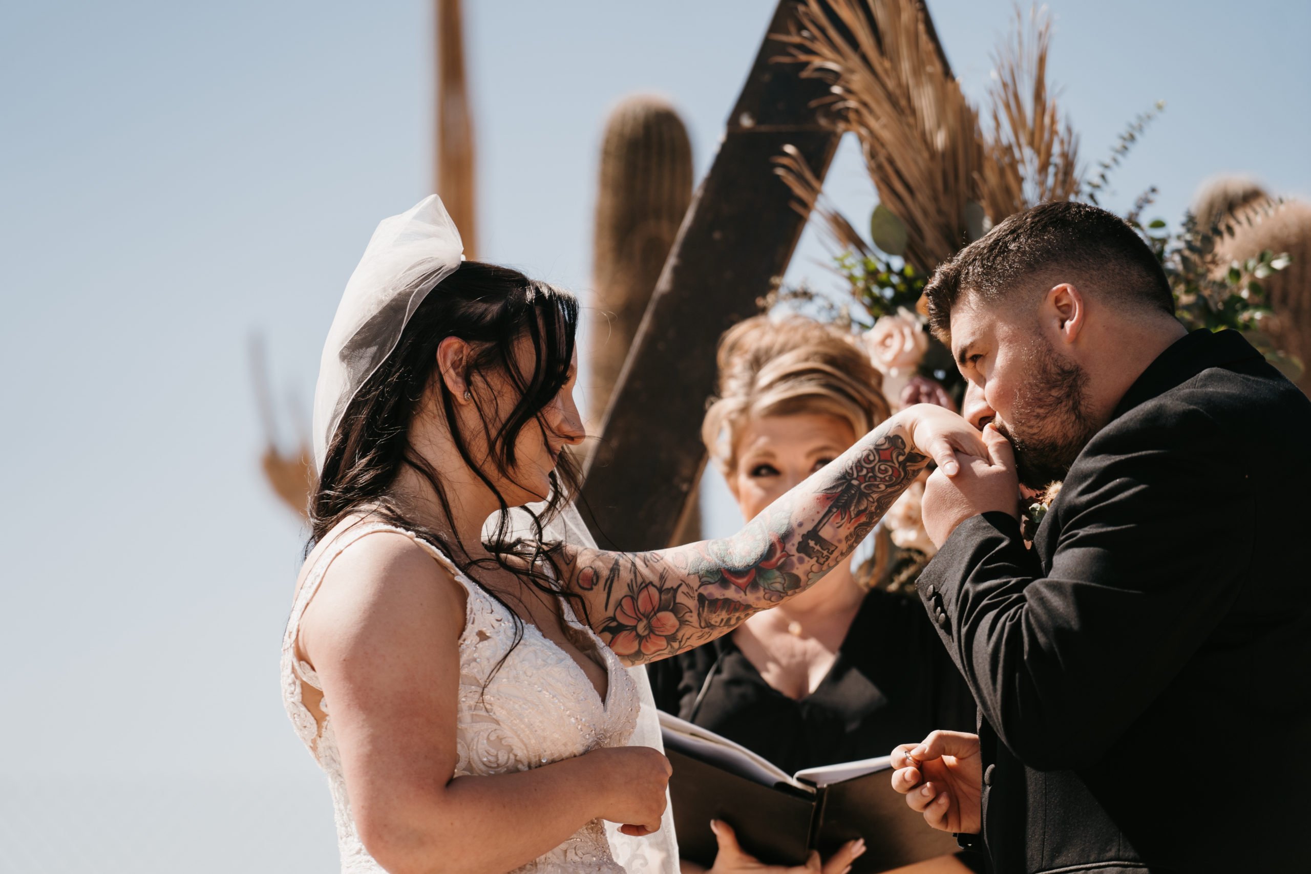 Groom kissing brides hand during ceremony 
