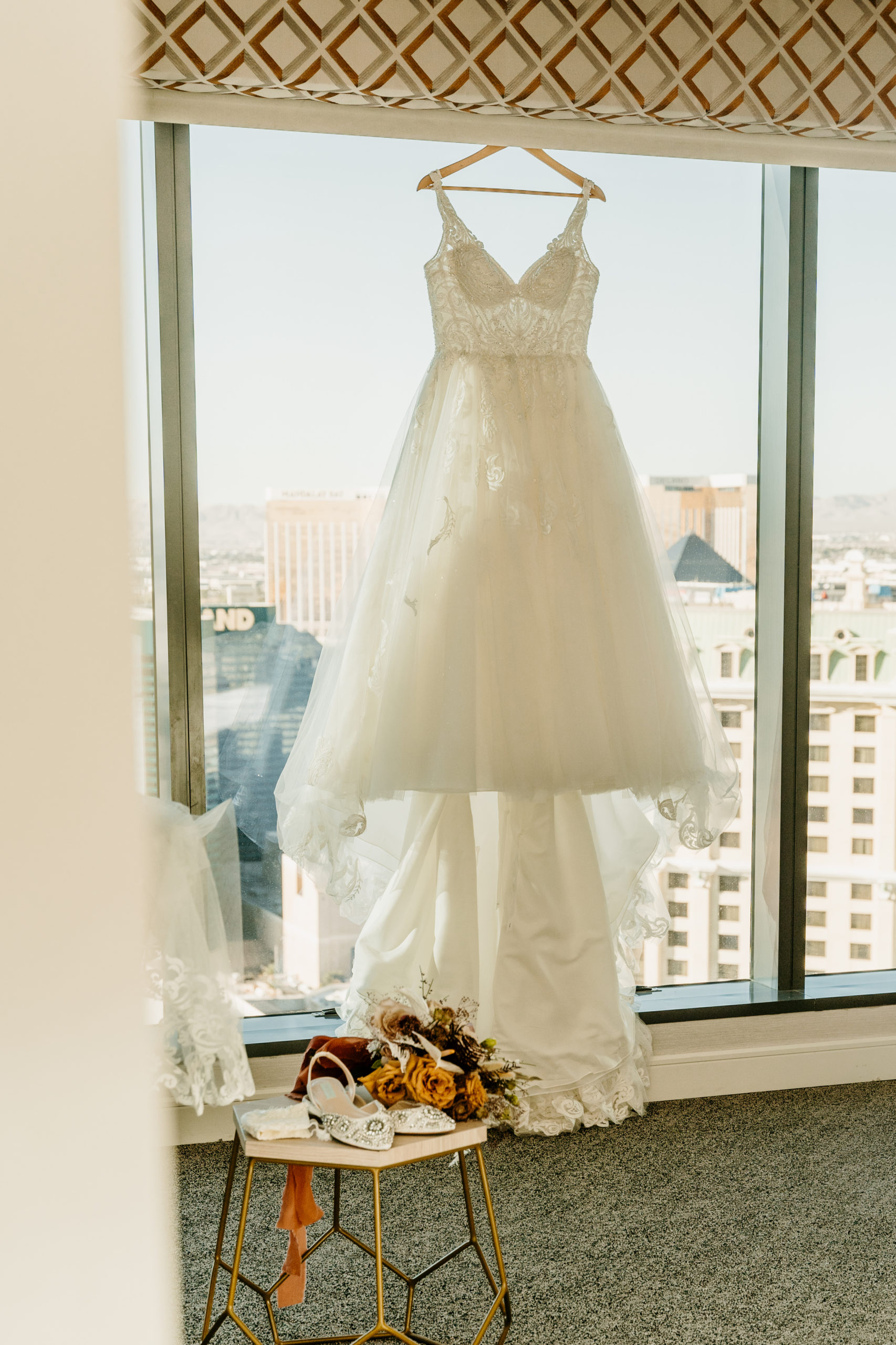 Brides dress hanging in front of window
