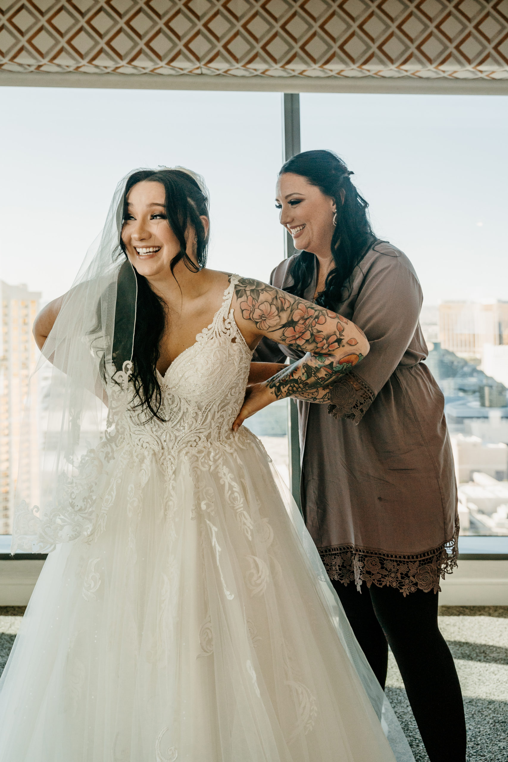 Bride getting dress buttoned by friend 