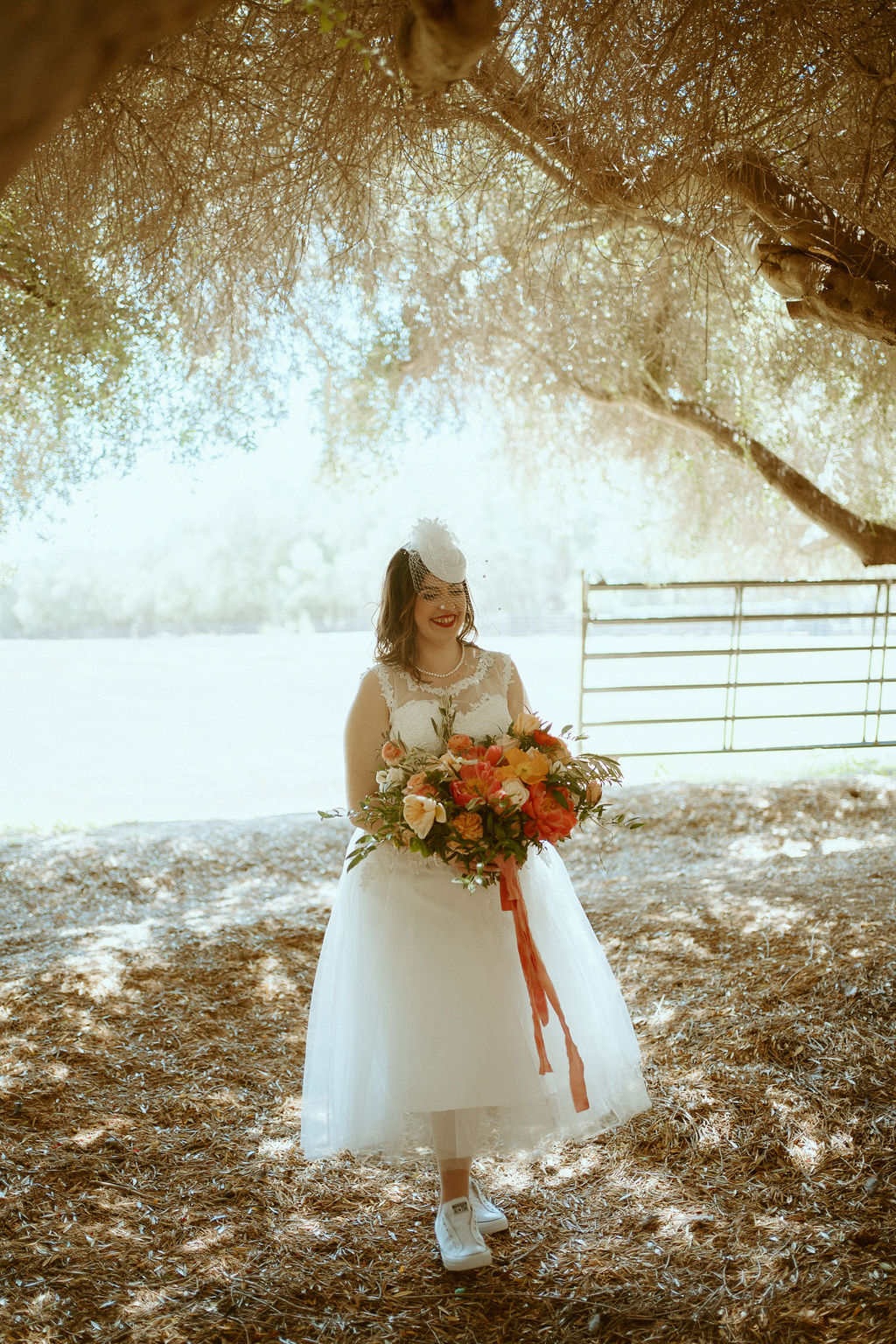Bride in birdcage veil walking down aisle with colorful bouquet 