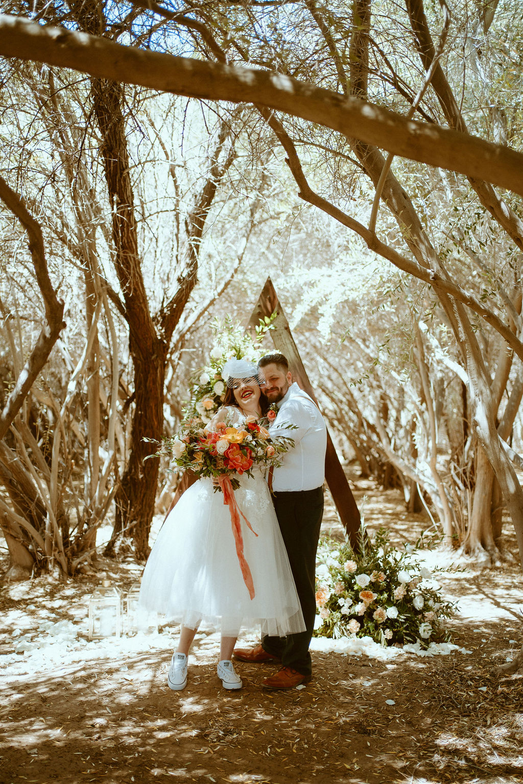 Bride and Groom smiling under Vintage Triangle Arch 