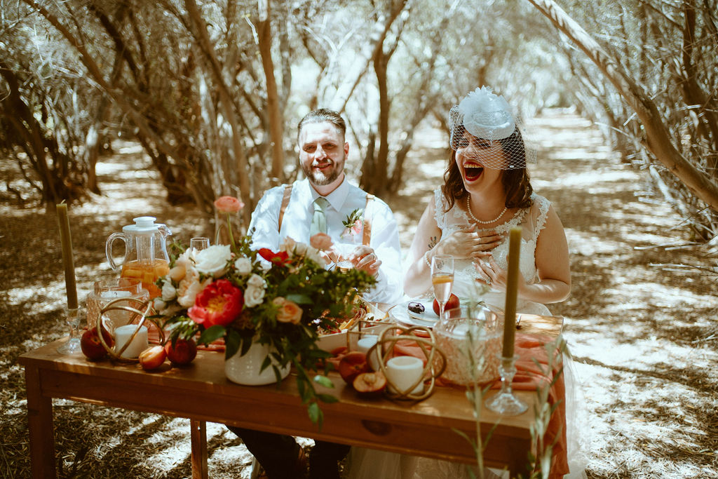 Couple laughing at sweetheart table with peach sangria 