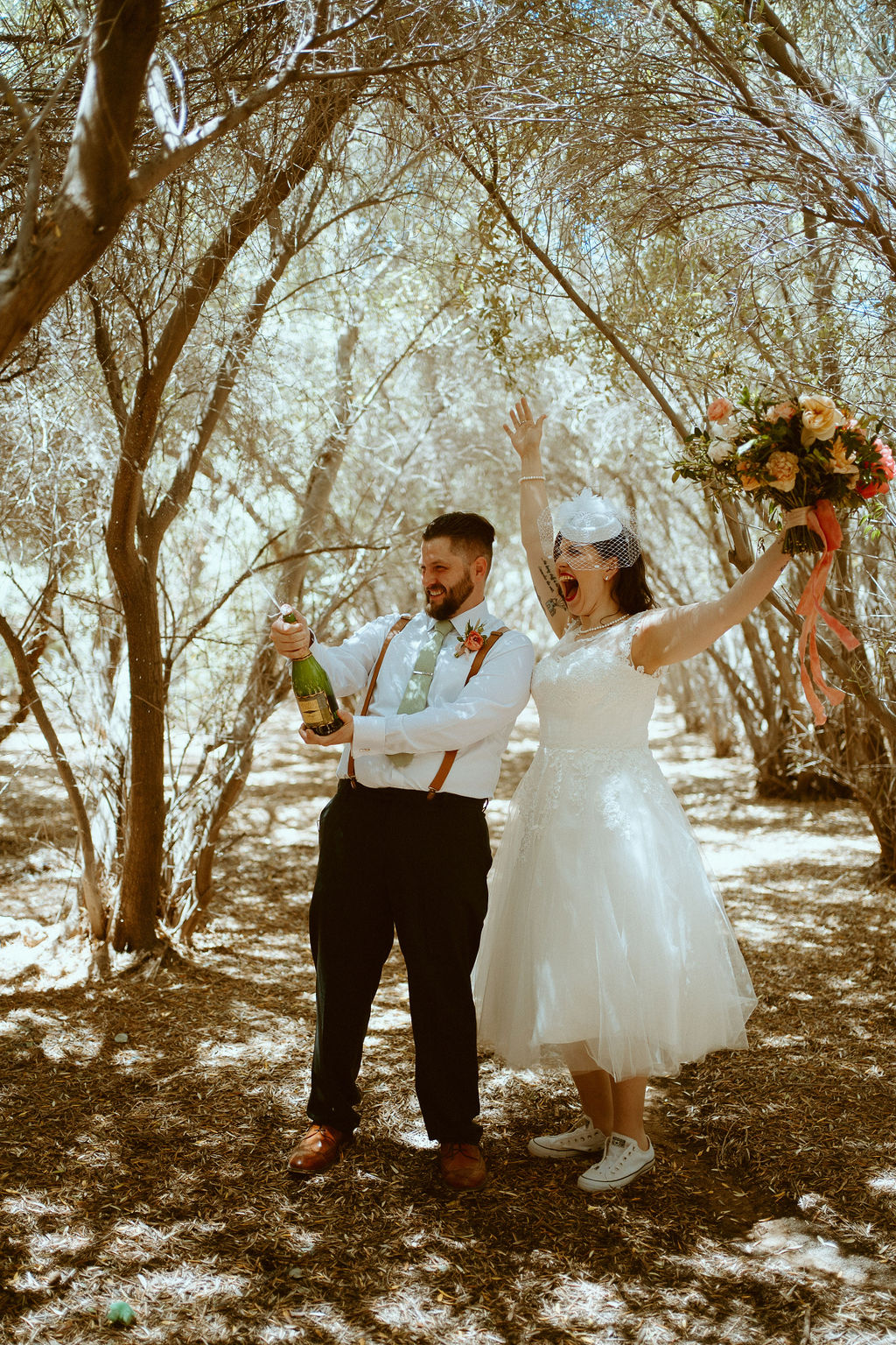 Couple popping champagne in vintage elopement 