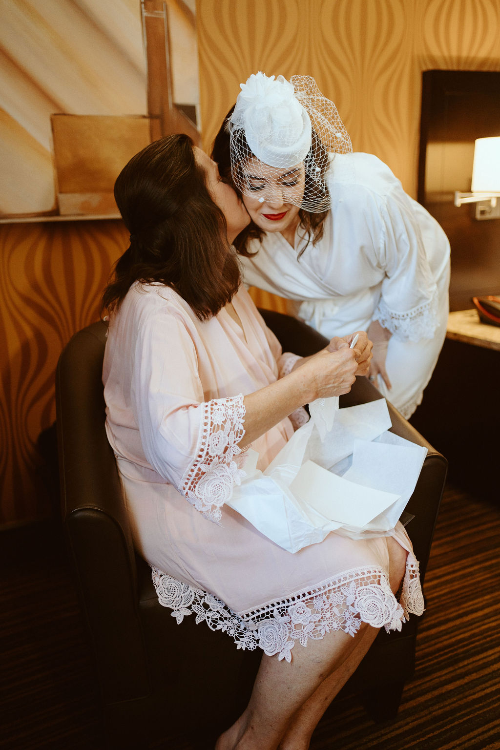 Mother of the bride kissing bride after receiving gift  