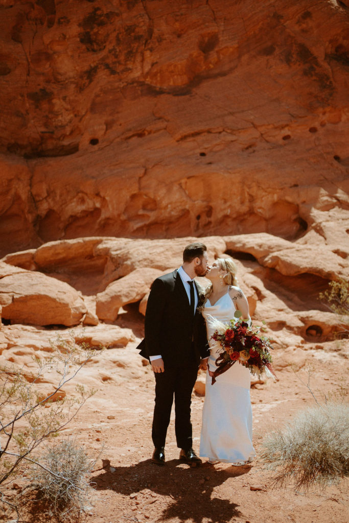 Bride and groom kissing one last time before going off to ceremony for their moody bohemian desert elopement 