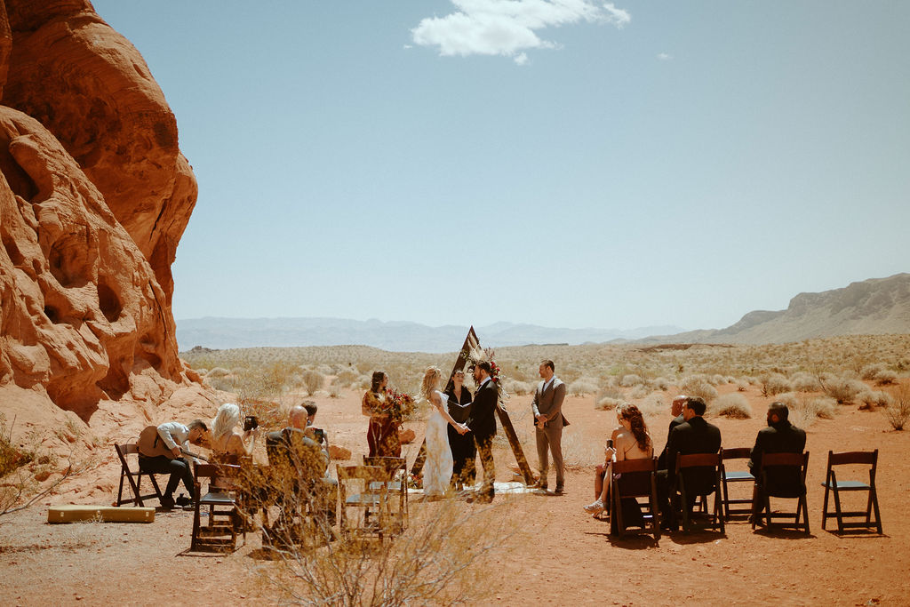 wide angle shot of entire moody bohemian ceremony at valley of fire with dramatic red rocks 