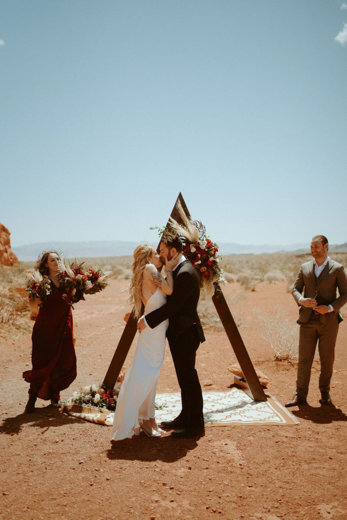 Bride and Grooms first kiss at valley of fire under moody bohemian arch 