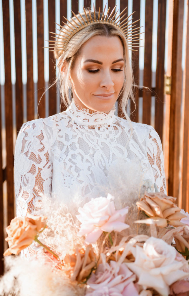 bride smiling and looking down at flowers wearing a headband as a statement accessory 