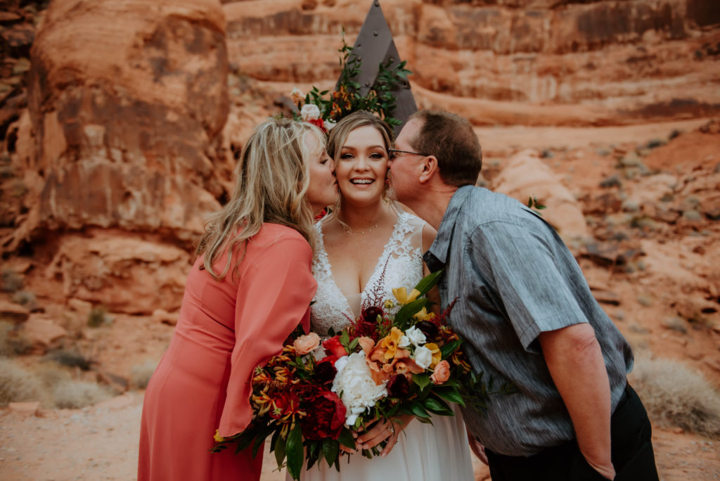 Mother and Father Kissing Bride on cheek after ceremony 