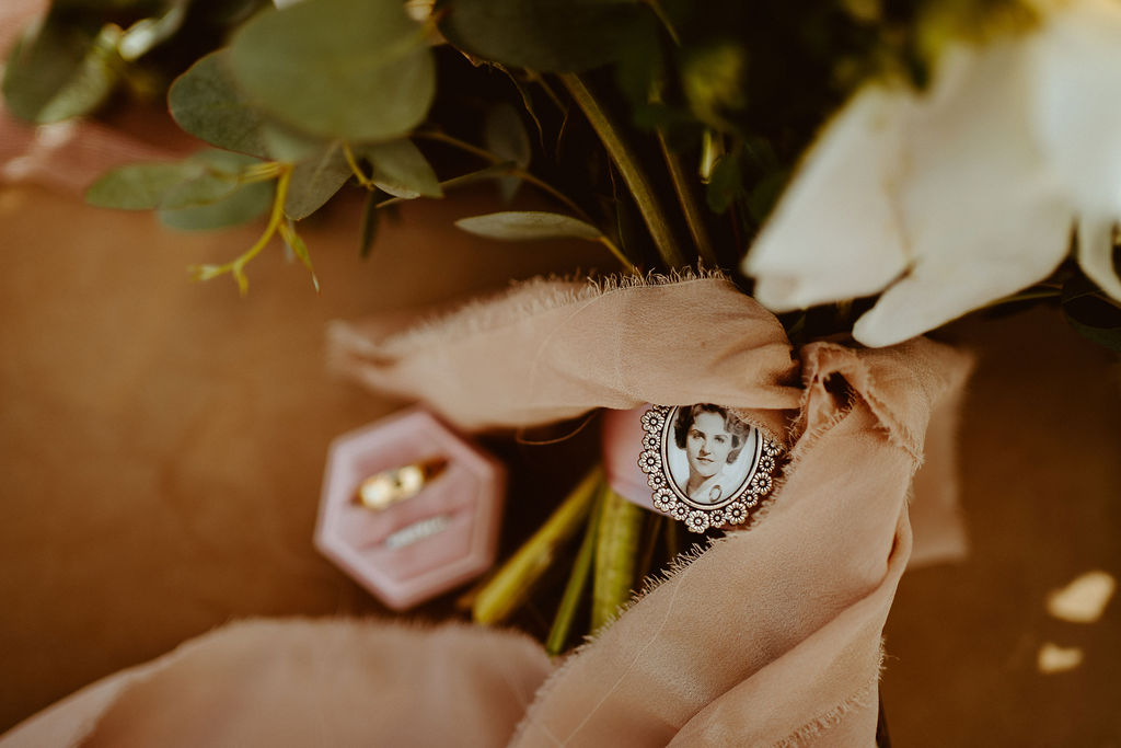 Pendant on Bouquet with wedding rings in the background 