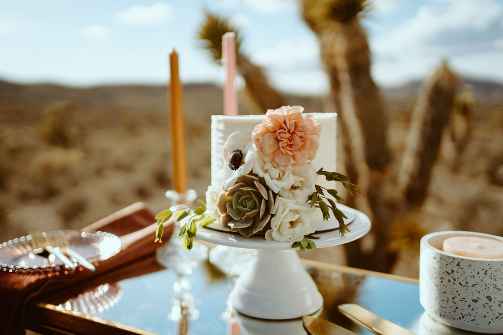 Cake with florals and succulents on table with candles during Kyle Canyon Timeless Desert Elopement