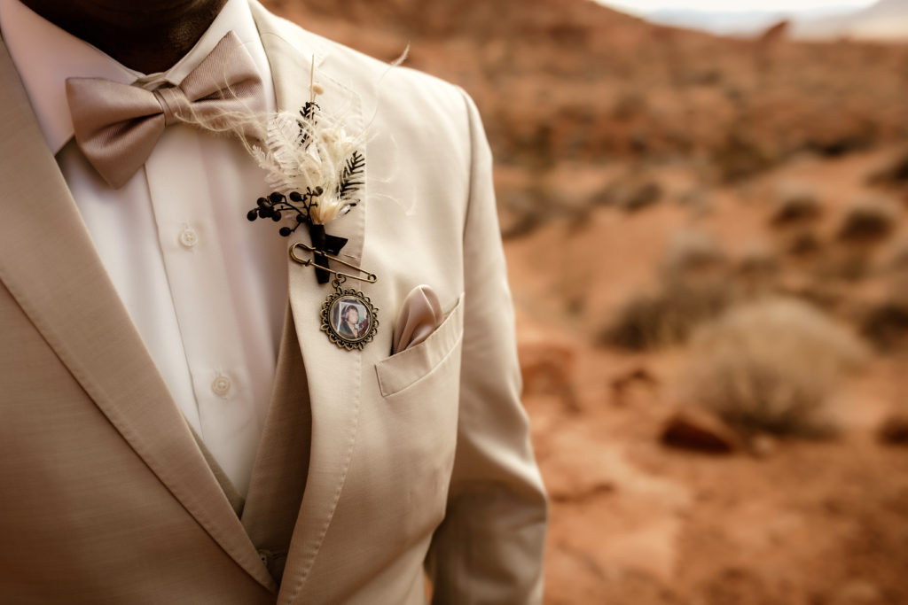 groom with locket of loved on pinned to suit on wedding day 