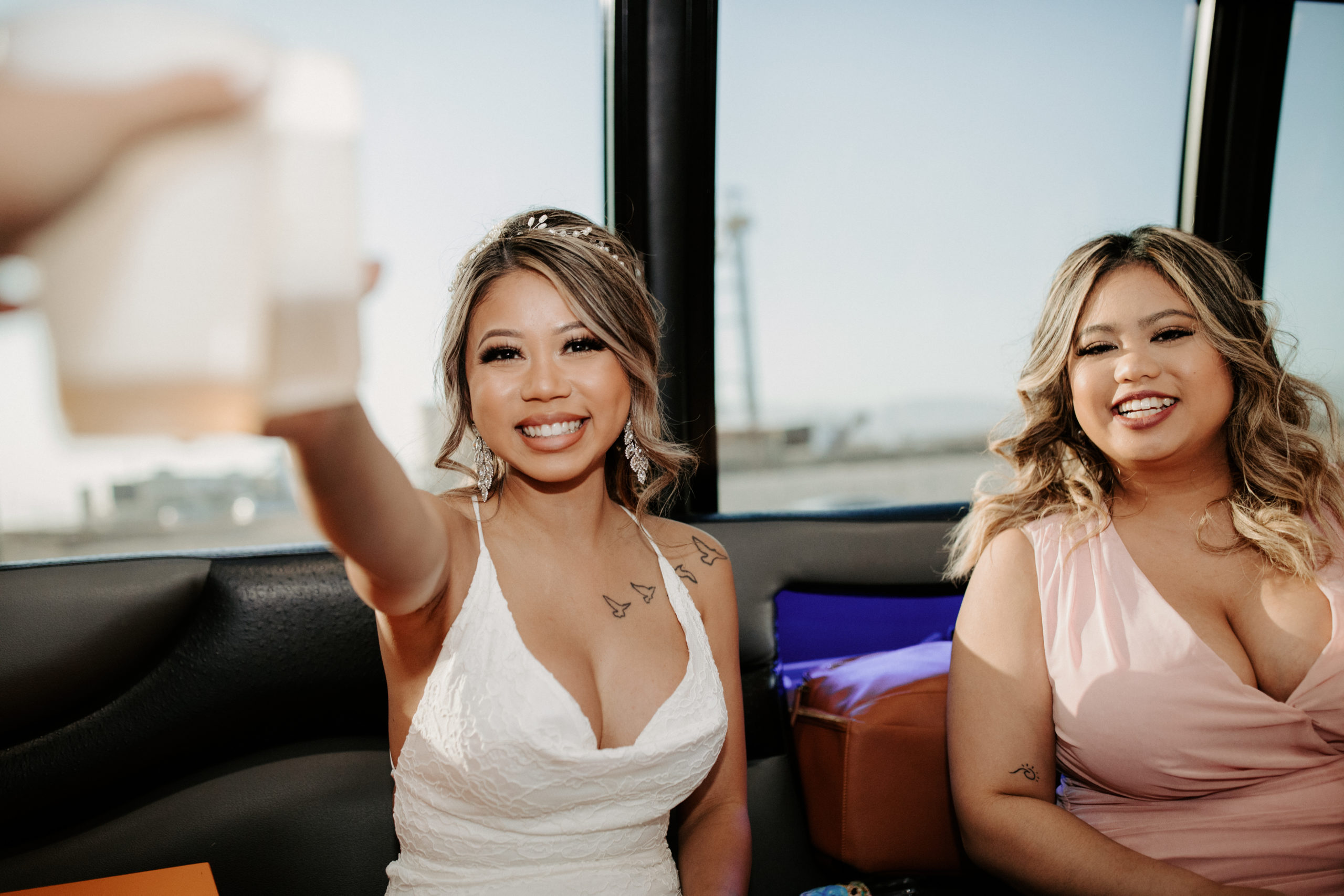 Bride doing a cheers while on party bus on the way to ceremony 