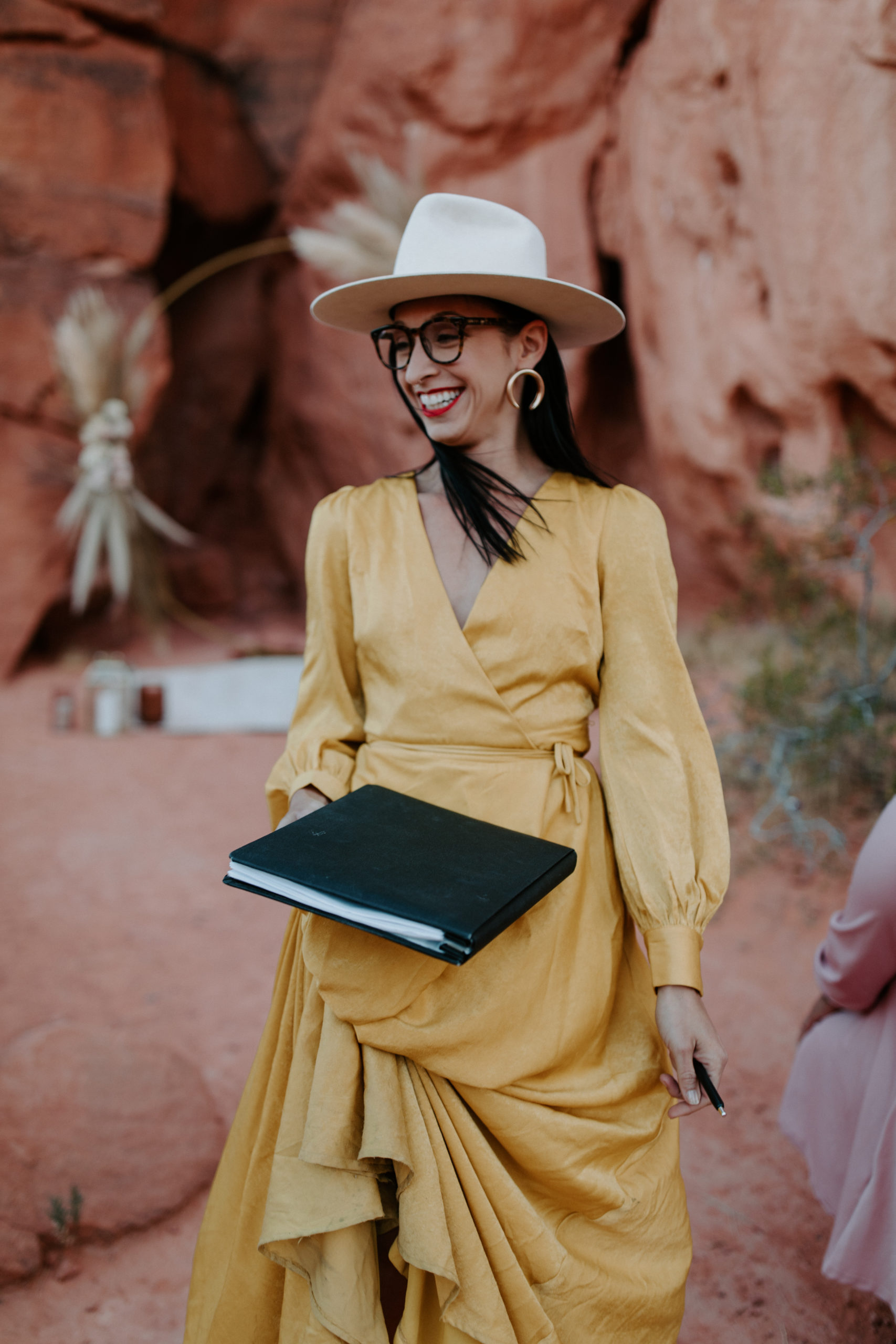 Officiant in yellow dress and hat prepping for elopement ceremony in Valley of Fire 