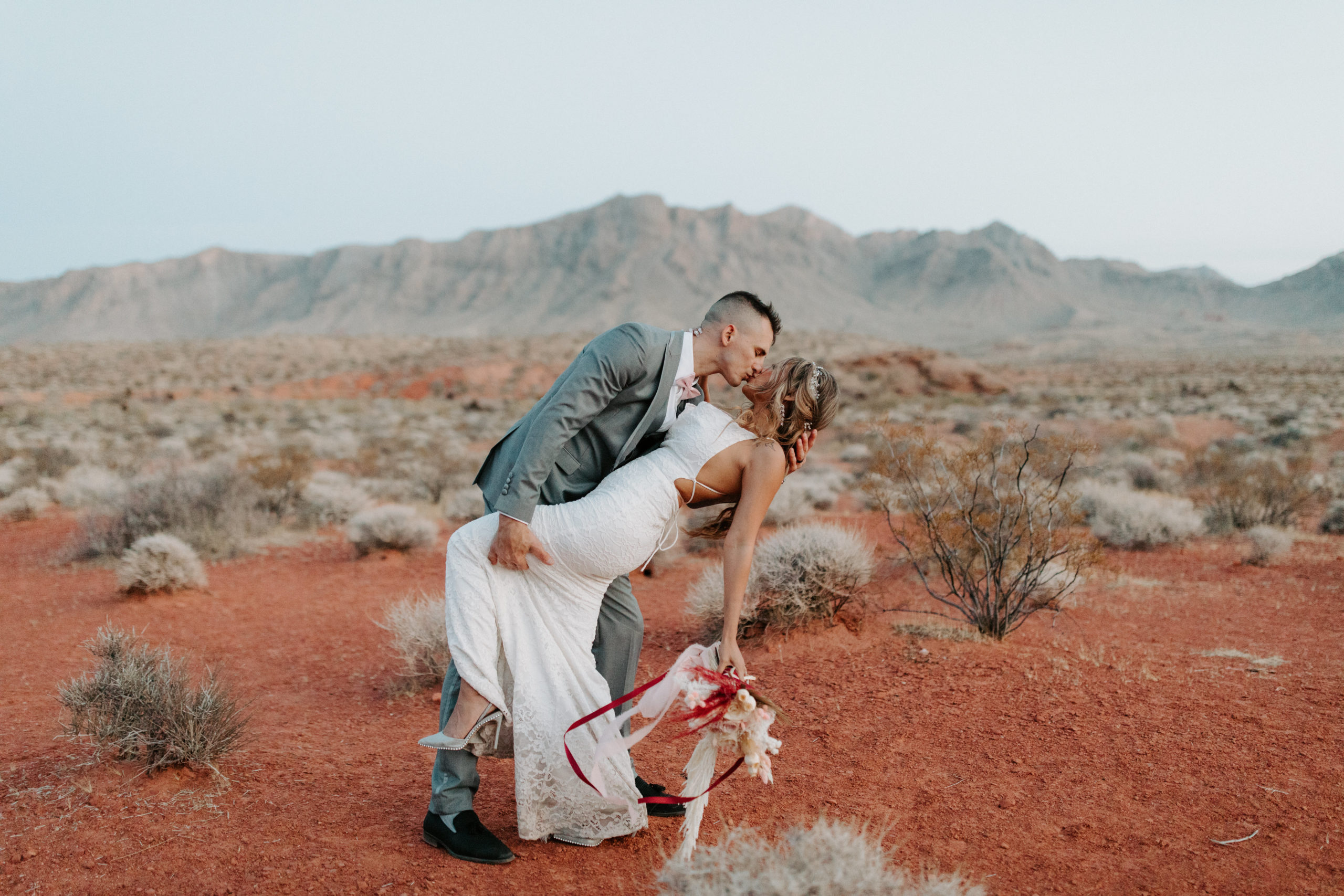 Newlyweds dancing and kissing in red desert Valley of Fire after elopement ceremony 