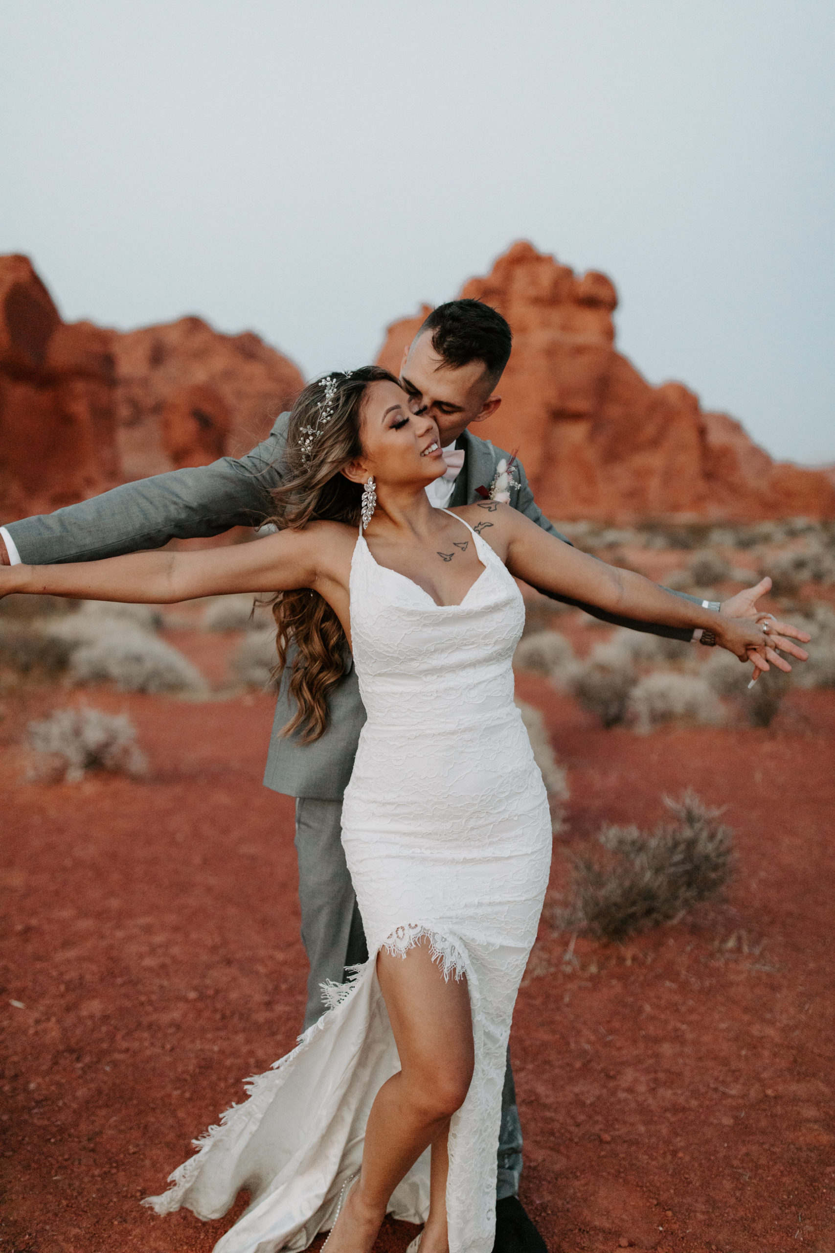 Newlyweds holding arms out and dancing in desert 