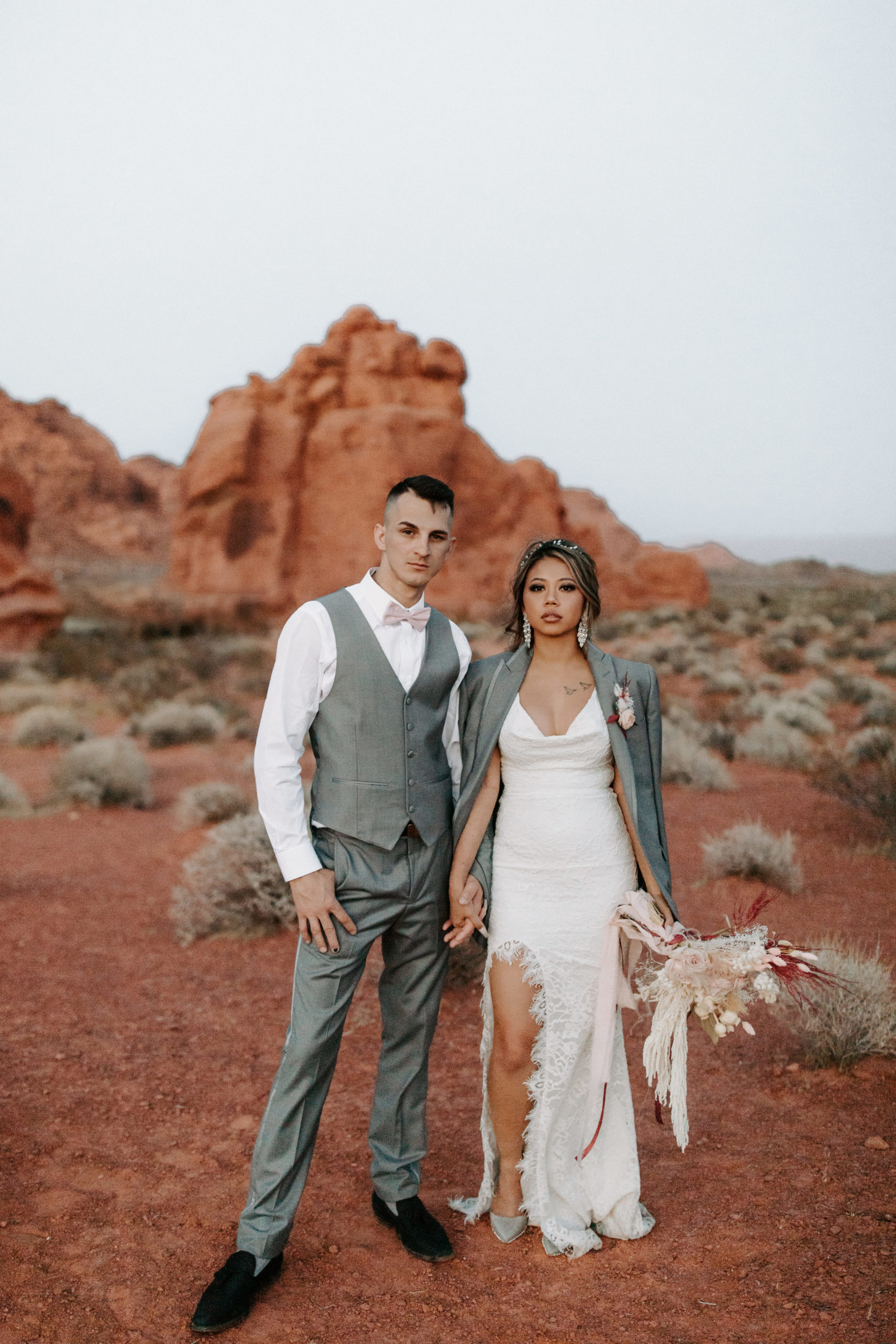 Bride wearing groom's gray jacket while in Valley of Fire for elopement 