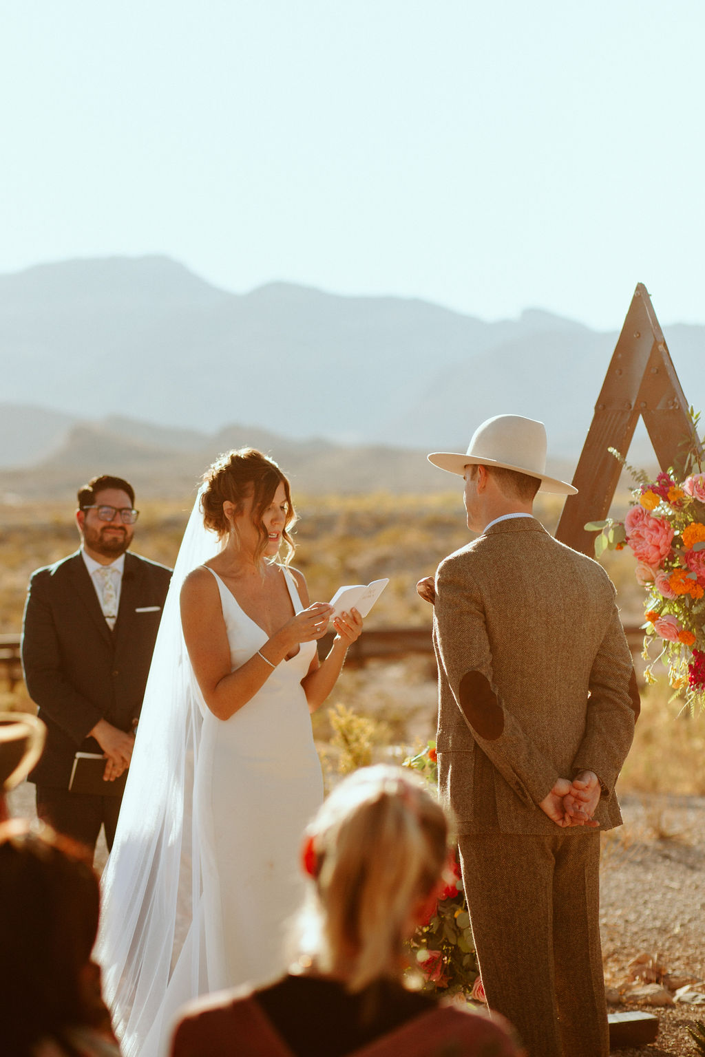 Bride reading groom in tween suit her vows in Desert Wedding 