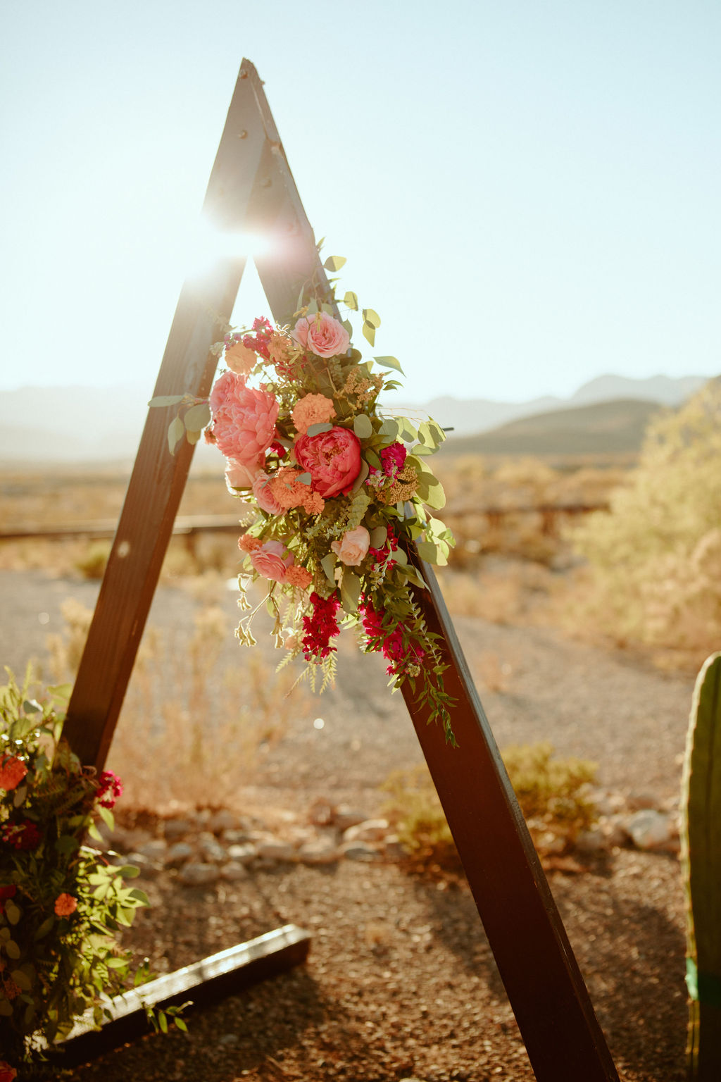 Colorful Wedding Florals with Peach and Bright Pink Florals on Triangle Arch 