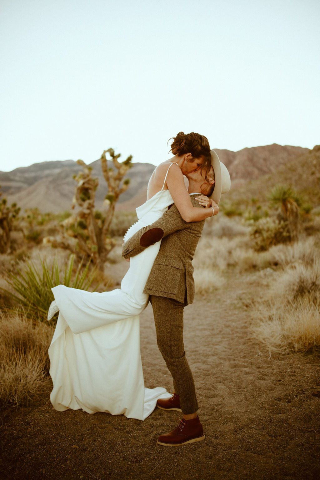 Groom lifting bride up in desert after Bright & Bold Sunset Desert Wedding 