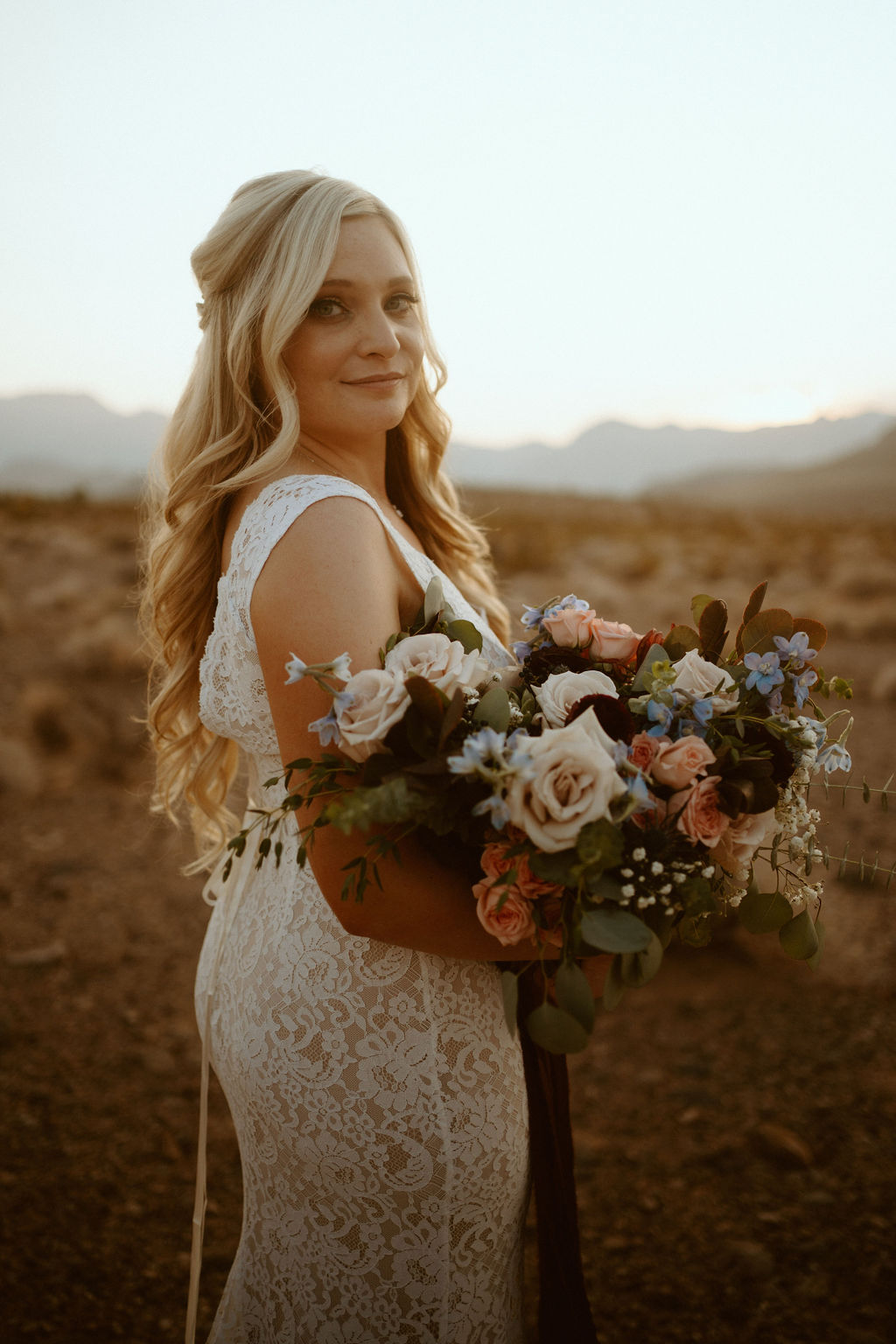 Bride holding Bouquet that is Dusty Blush, Dusty Blue, Off-white, Eucalyptus, Sage Green 