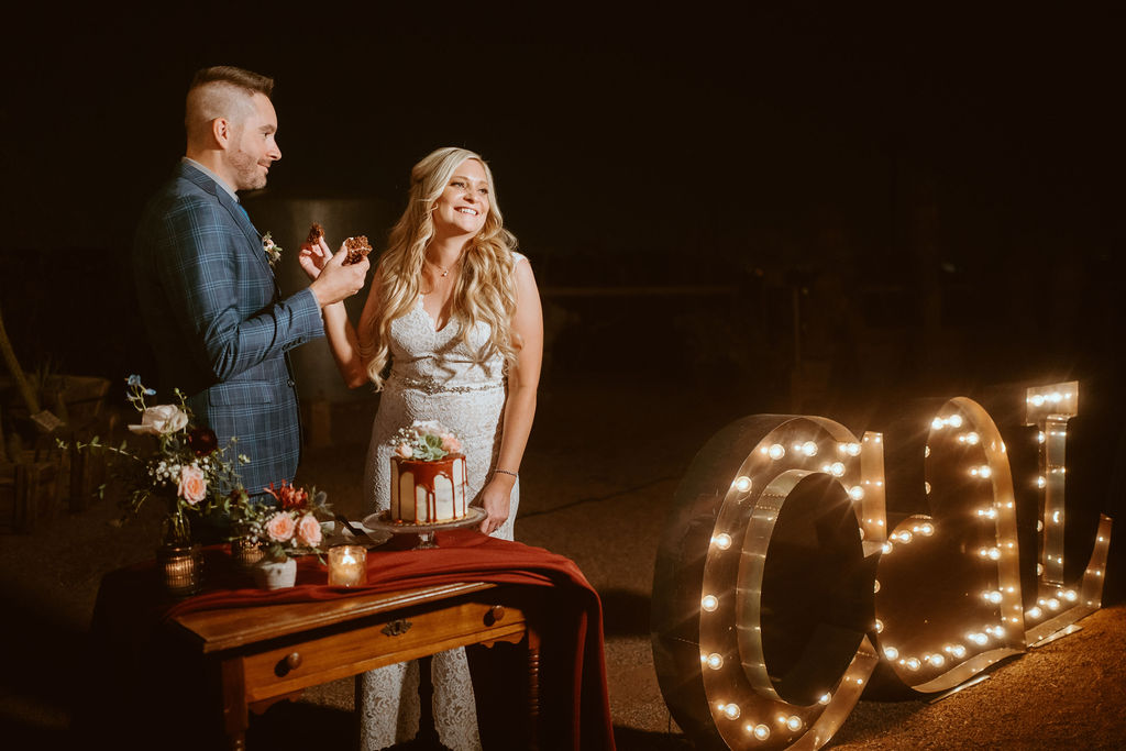 Bride and Groom Feeing Each other Drip Wedding Cake with Custom Marquee Letters 