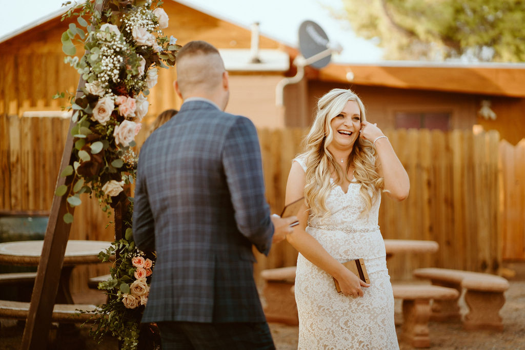 Bride Laughing While Groom Reads her his Vows 