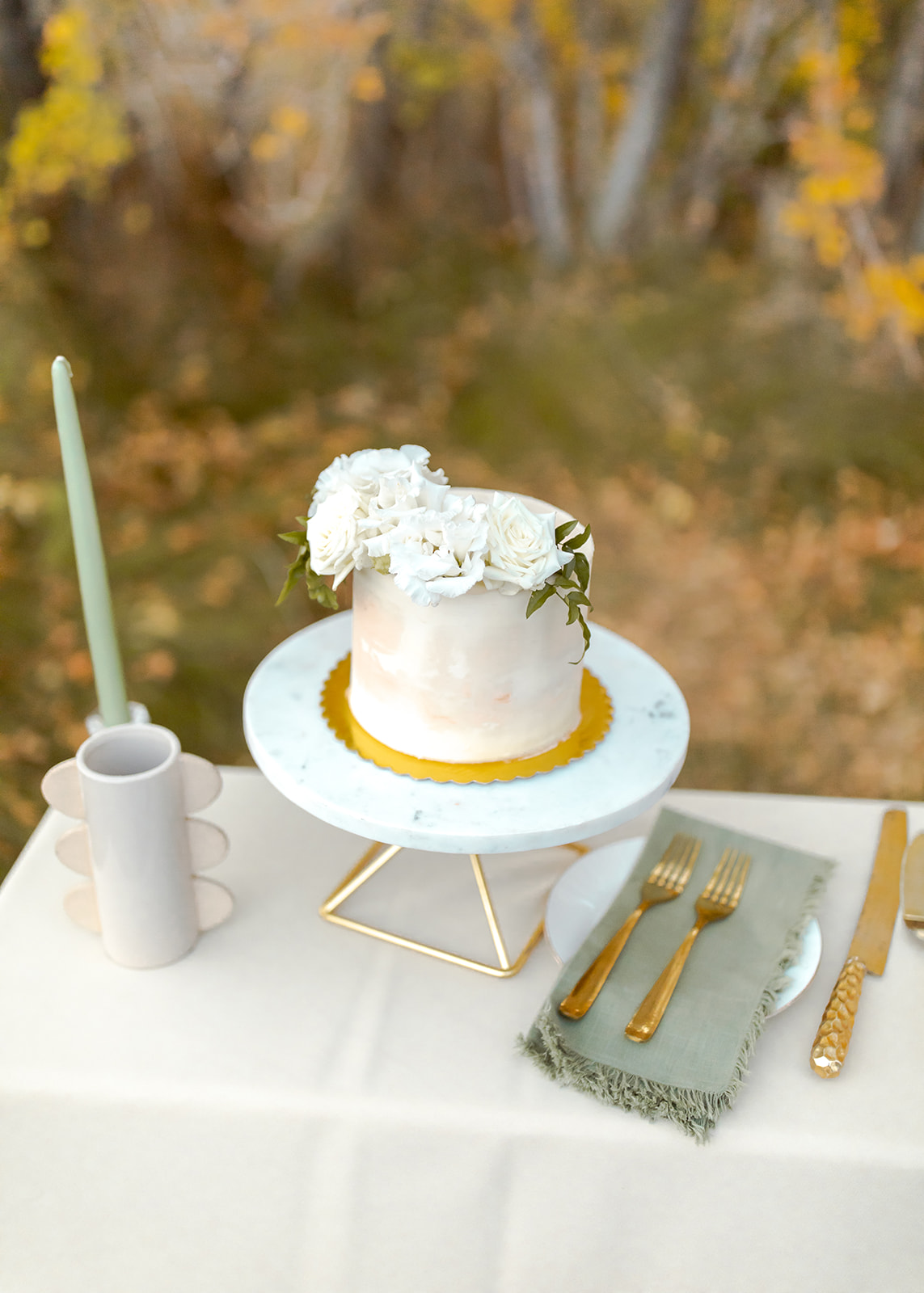 White 1 tier textured cake with sage napkins and gold flatware for white, sage, gold, and greenery fall theme