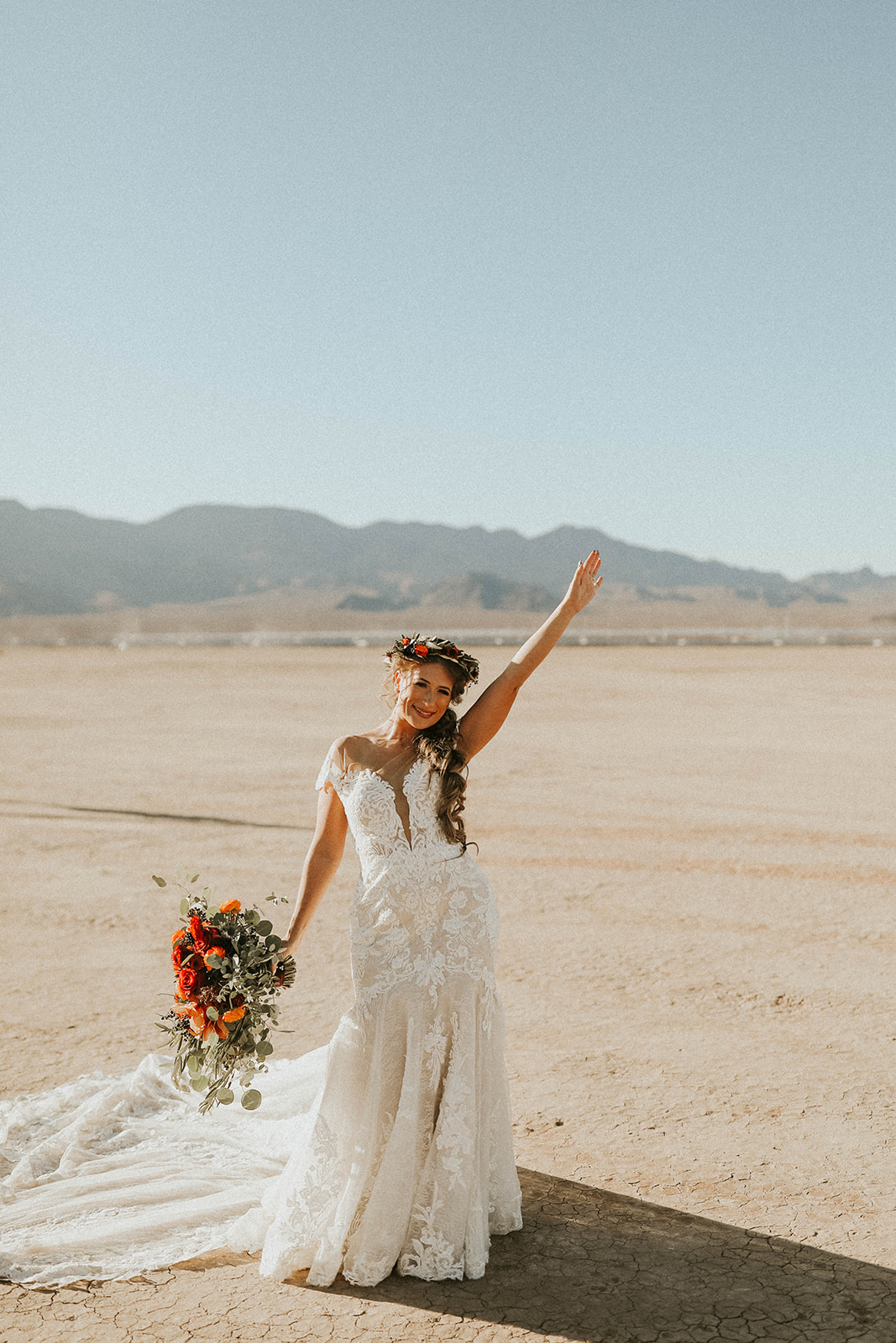 Bride with Floral Crown & Holding Bouquet with one arm up in excitement before ceremony in Dry Lake Bed Fall Inspired Elopement 