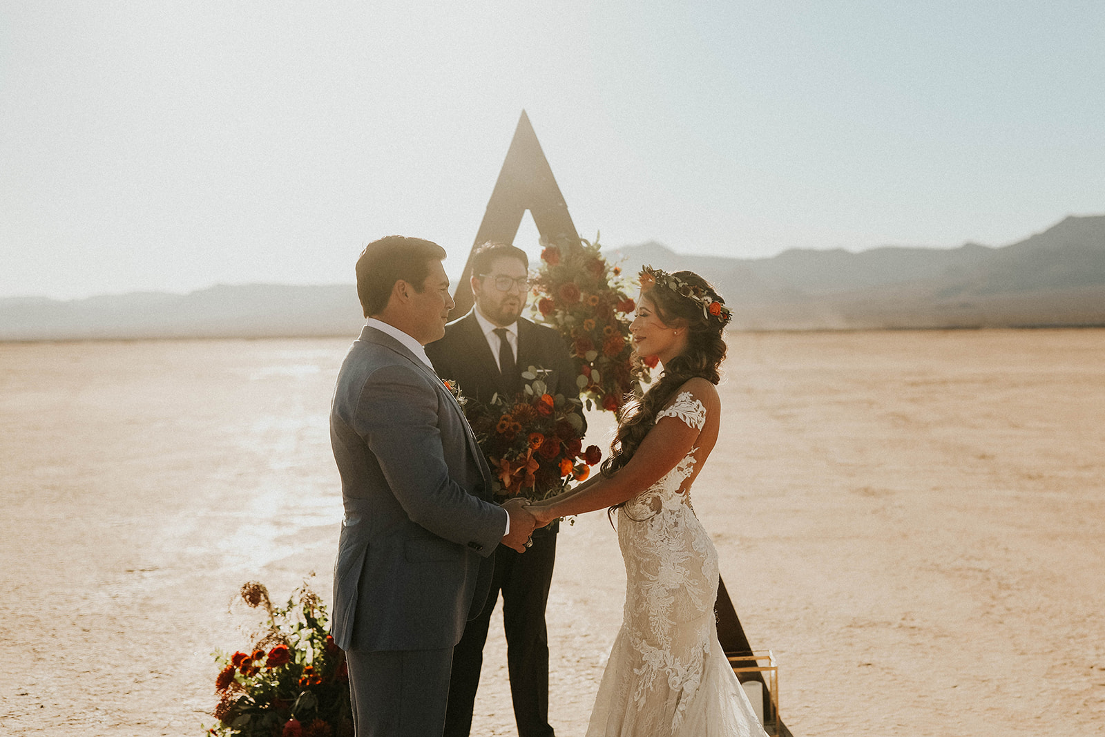 Bride & Groom Holdings Hands under Triangle Arch will getting Married in Dry Lake Bed Fall Inspired Elopement 