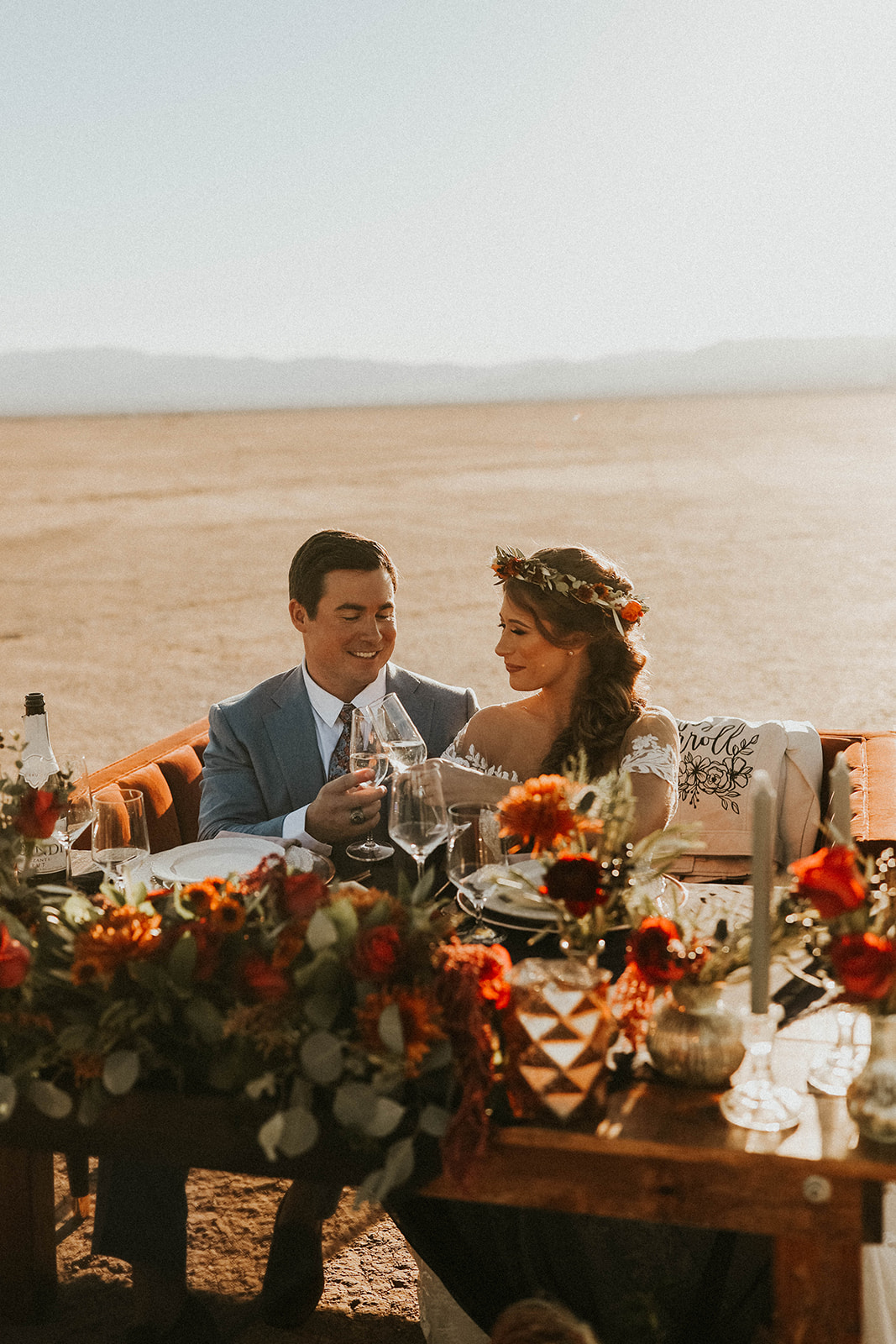 Newlyweds Having Champagne while Sitting at Dry Lake Bed Fall Inspired Elopement Sweetheart Table with Velvet Couch & Fall Inspired Floral 