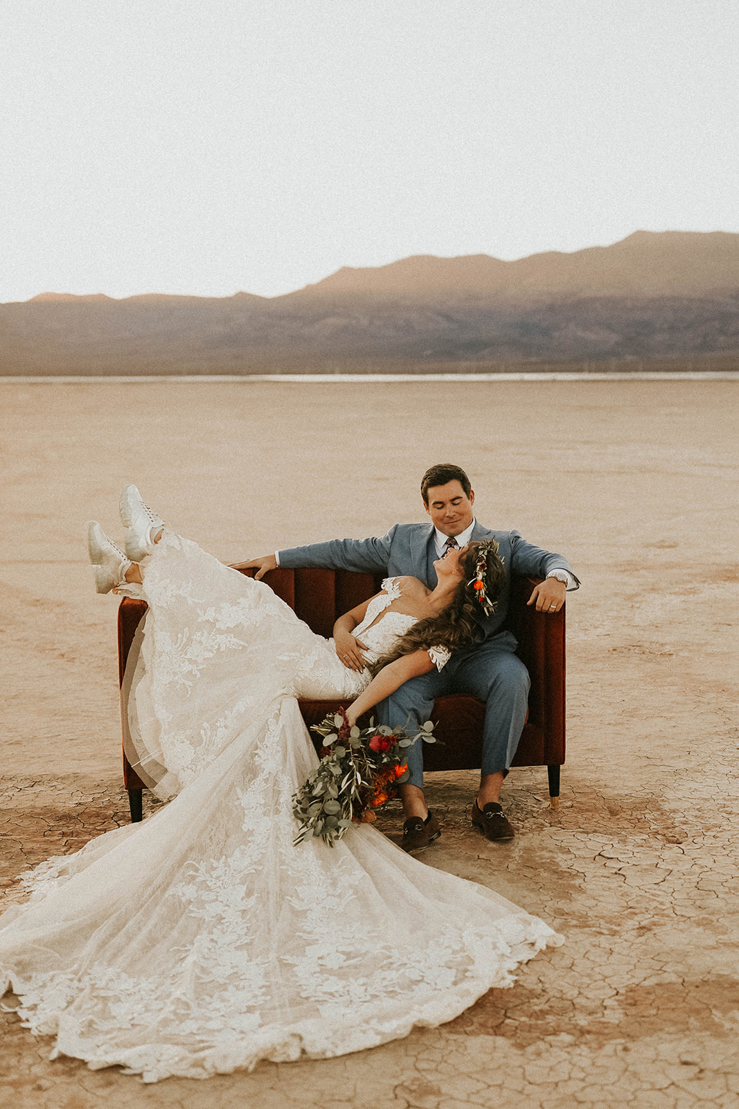 Newlyweds Looking at each other on Velvet Couch during Sunset in Dry Lake Bed Fall Inspired Elopement in Las Vegas