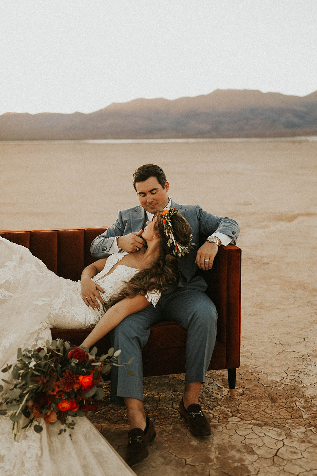 Groom touching Bride's face on Velvet Couch during Sunset in Dry Lake Bed Fall Inspired Elopement in Las Vegas