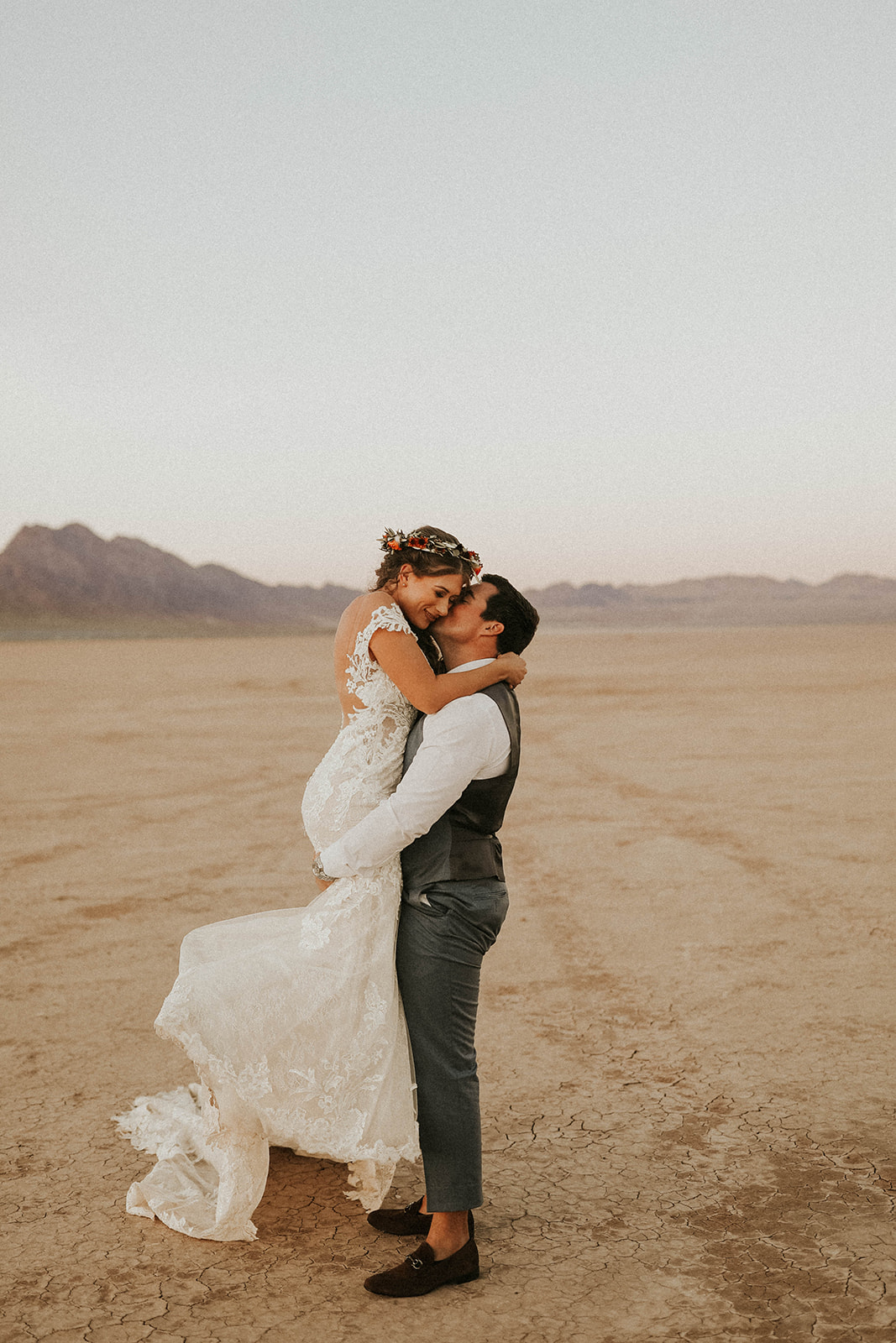 Groom Holding Bride & Kissing Cheek on Dry Lake Bed 