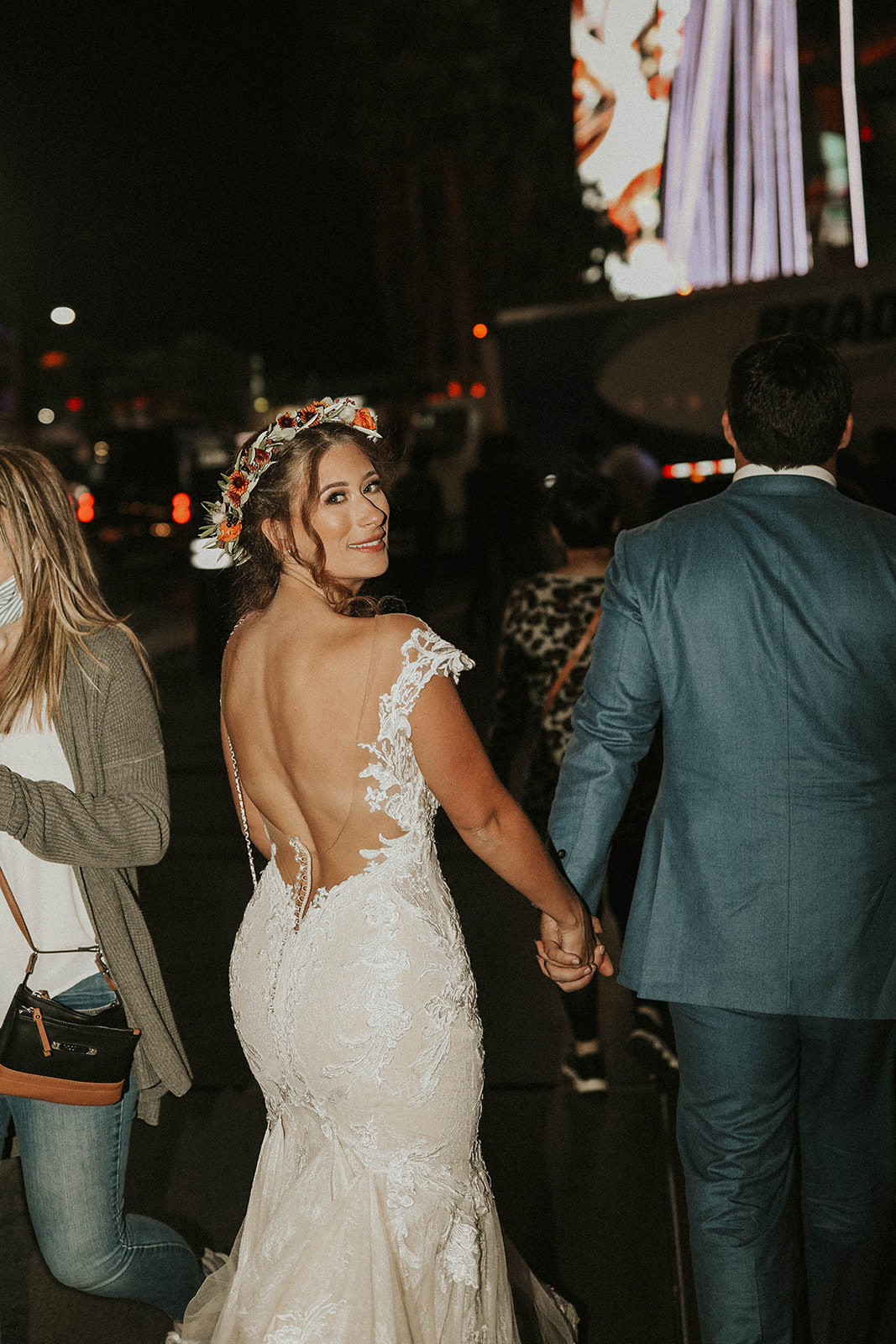 Bride with Floral Crown Looking Back While Walking Through Busy Las Vegas Strip 